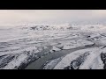 high aerial view of snow covered iceland with a long flowing river during