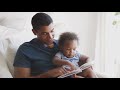 videoblocks millennial african american father sitting and reading a book with his toddler son front