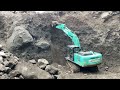 Mining sand around large rocks using Kobelco excavator heavy equipment