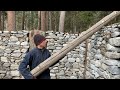 Building a stone and wood survival bushcraft shelter in the woods