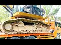 The process of lifting and lowering a Caterpillar excavator onto a self-loader.